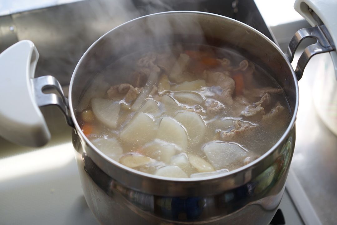 婆婆先將配料放進湯裡煮，有白蘿蔔，紅蘿蔔增添湯頭的甜味以及豬肉增加油香味
